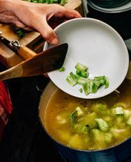 Broccoli stems being added to a pot of soup.